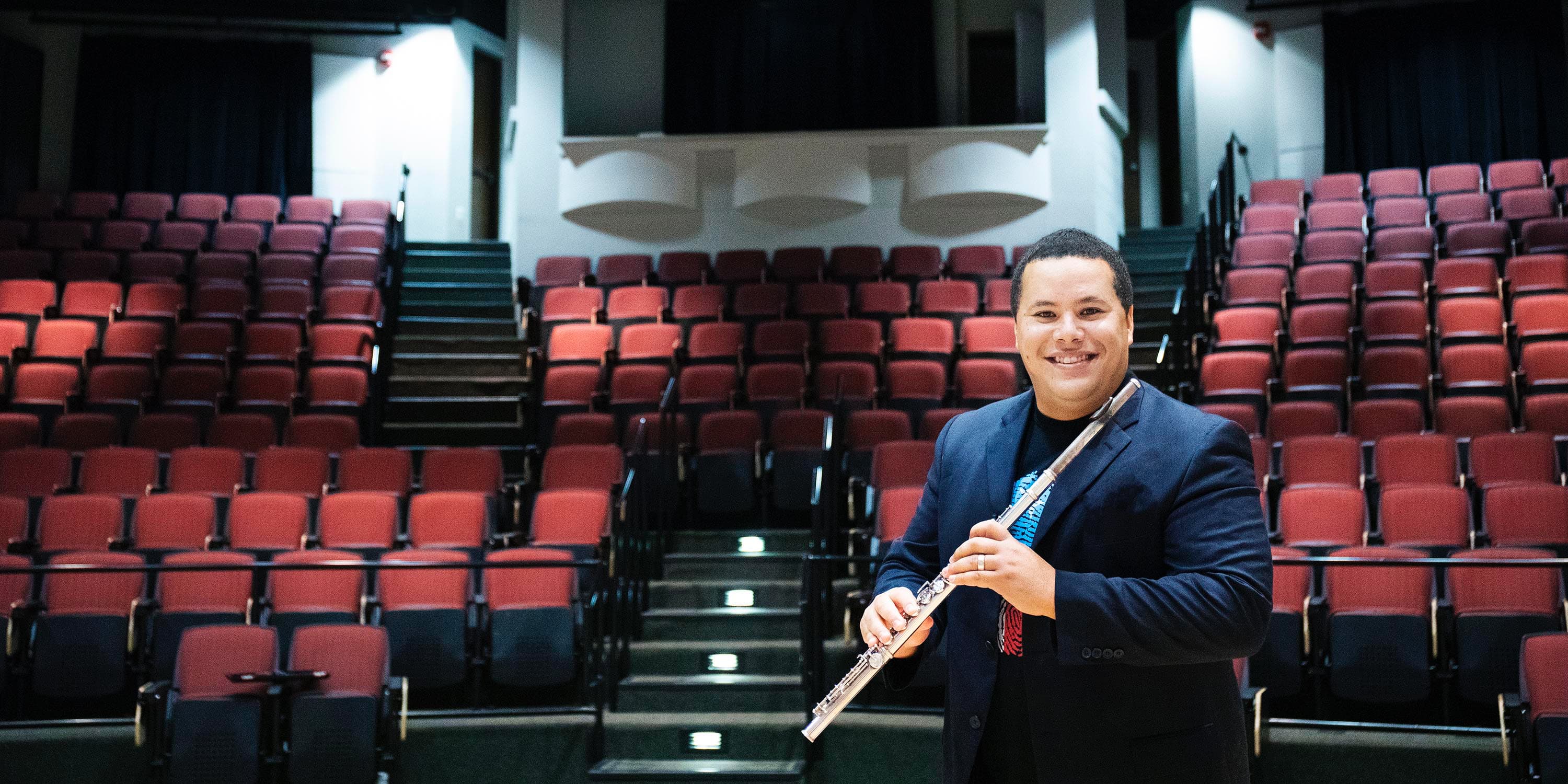 Professor Jose Valentino Ruiz holds a flute in a concert venue at the University of Florida 