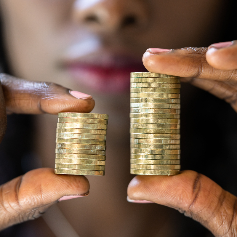 Close up of a person's hands holding more coins on the right than the left